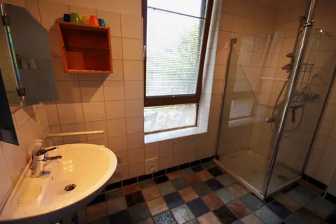 Badezimmer im Vormannshuus mit Waschbecken, bunt gefliestem Boden und Echtglasdusche