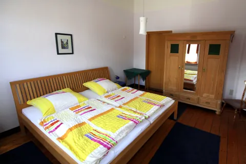 Schlafzimmer im Vormannshuus mit Doppelbett aus Holz und Kleiderschrank