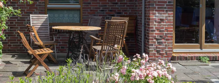 Sitzplatz auf der Terrasse des Vormannshuus mit Holzstühlen, Lavendel und Rosen