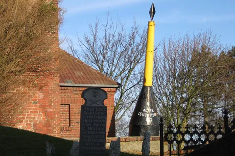 Alter Leuchtturm von Borkum aus Backstein mit Gedenkstein und gelb-schwarzem Seezeichen